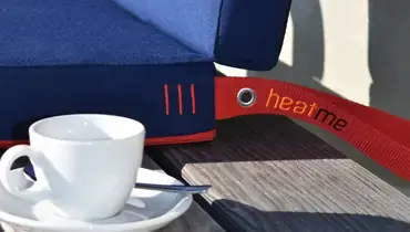 Zandkleurig verwarmingskussen op houten stoel van een cafeterras