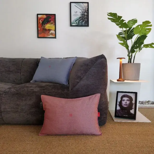 Vrouw ontspant met het heatme HOME verwarmingskussen in hemelsblauw op een sofa